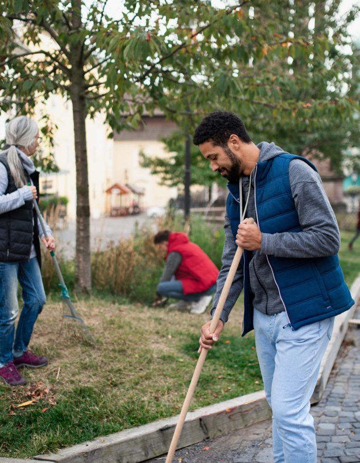 A young man volunteer with team cleaning up street, community service concept